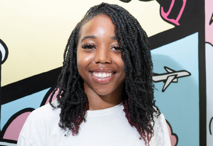 smiling young women standing next to a colourful mural