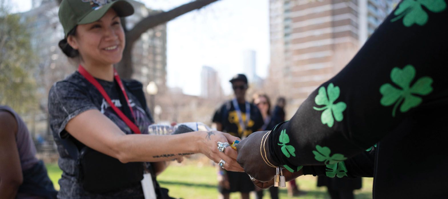 woman in park handing out supplies to encampment residents