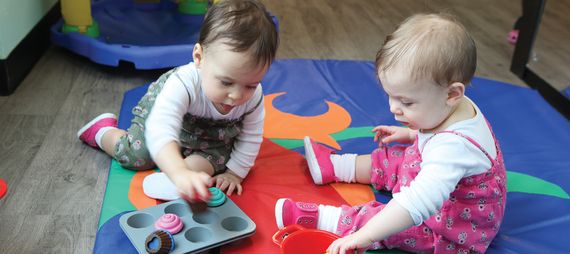 two toddlers playing on a mat