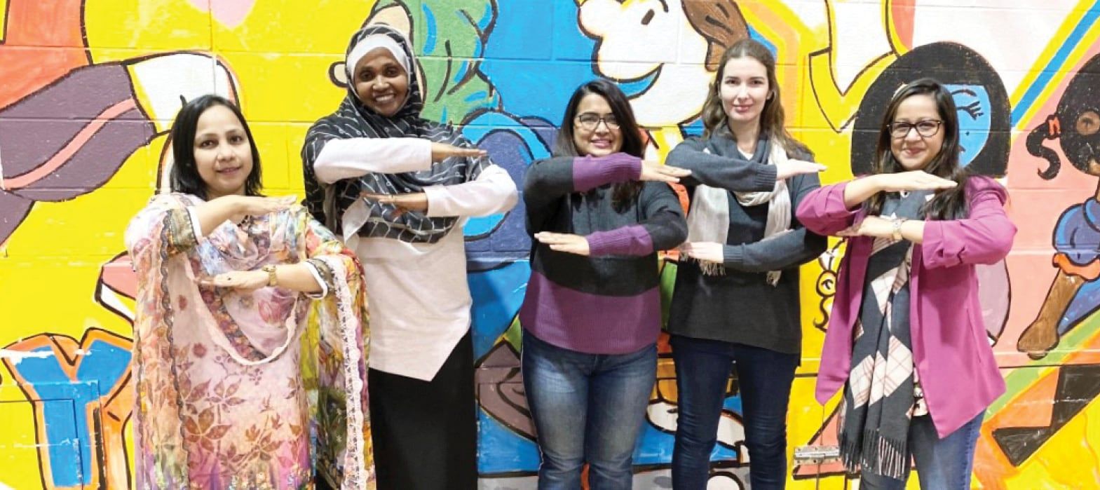 women posing against a wall mural