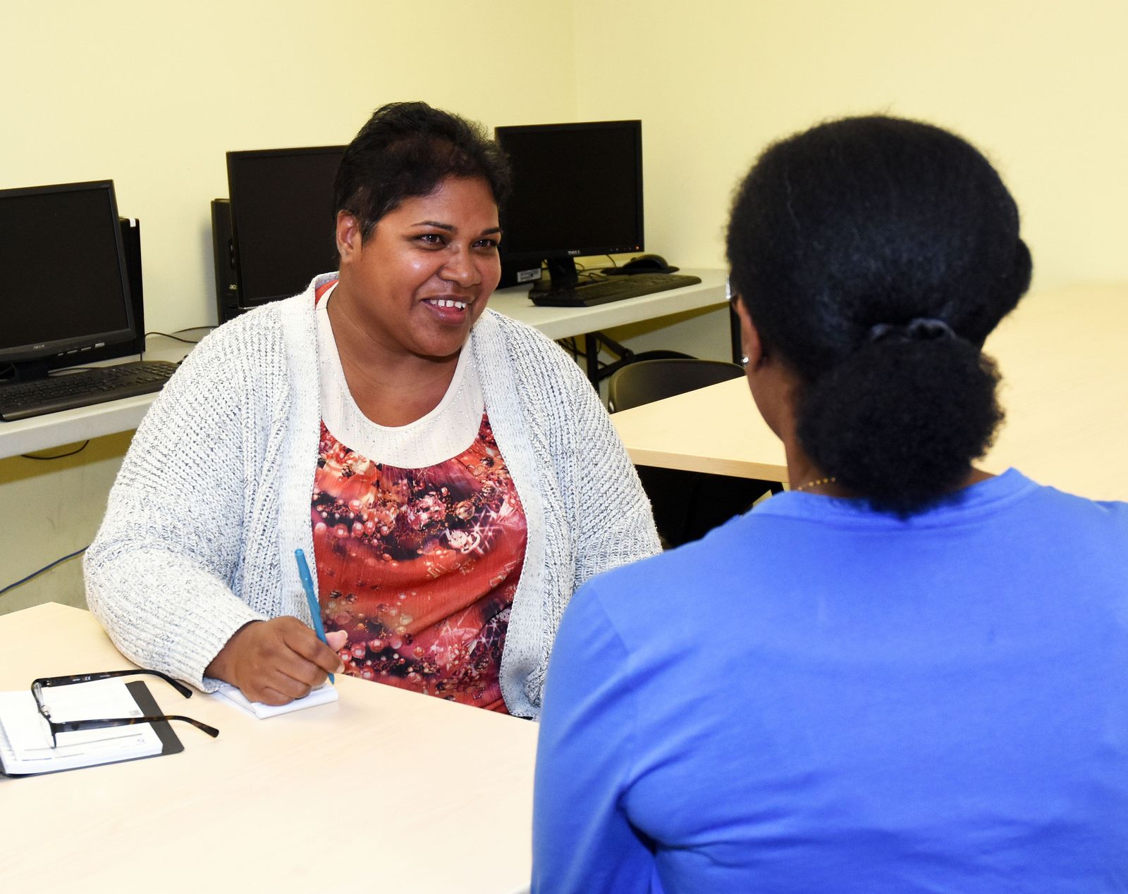 smiling women in a computer classroom talking to an instructor