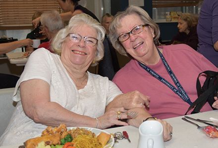 two smiling seniors at a dining table