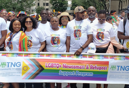 group of people wearing white Rainbow Connect signs and holding a banner with the text "LGBTQ+ newcomers and refugees support program"