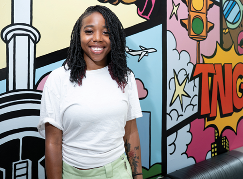 young woman standing in front of a colourful mural